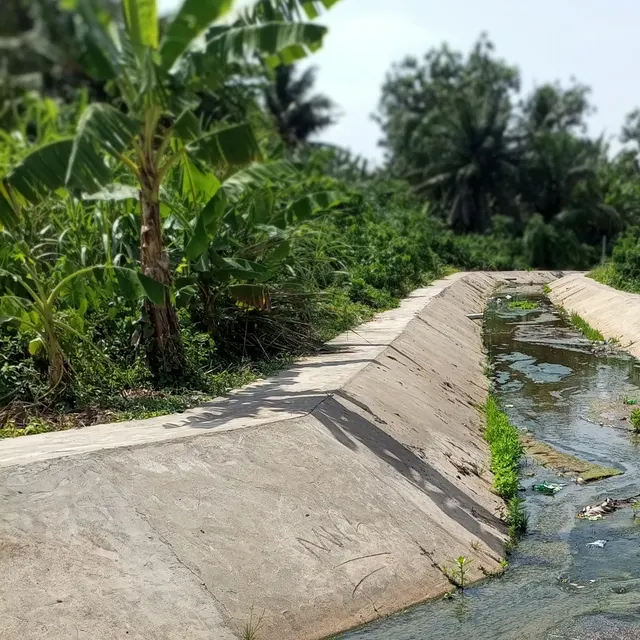 A concrete-lined open drainage channel beside a community road in Ibereko, Badagry, Lagos State. Openly licensed photograph by Macdanpets.